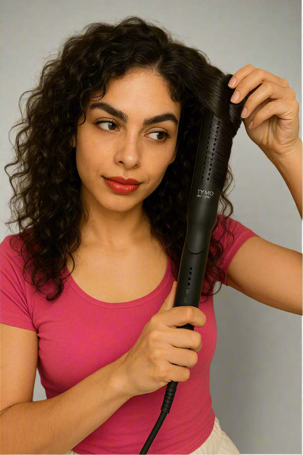 Woman using a hair straightener indoors